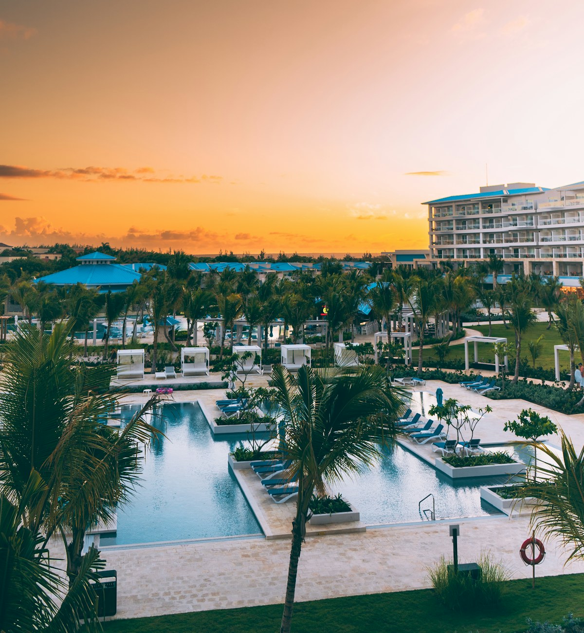 A palm-lined resort with pools and warm sunset light.