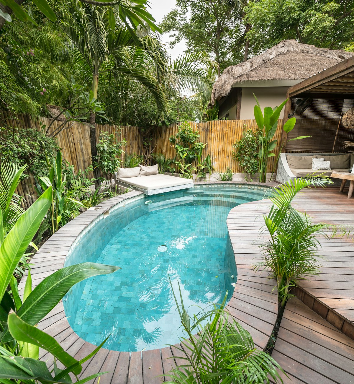 A private tropical villa with a curved swimming pool and lush garden.