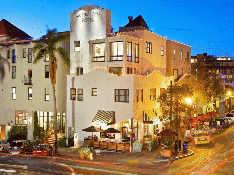 La Pensione Hotel in San Diego’s Little Italy at night, illuminated with warm lights and surrounded by vibrant city life—showcasing WaveBNB’s successful direct booking strategy that helped scale t