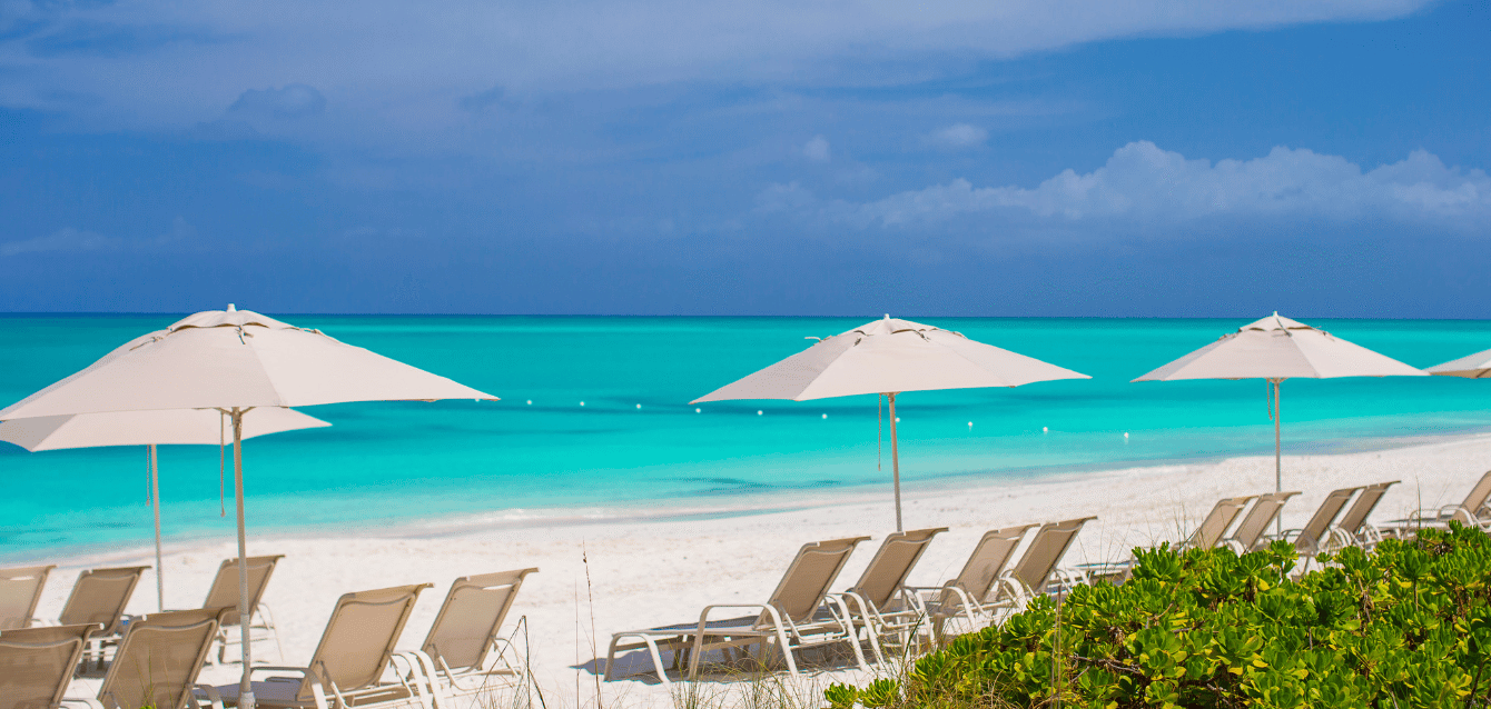 Serene beachfront lounge area with white umbrellas and sunbeds facing the ocean, highlighting the luxurious experience of a high-end boutique hotel—demonstrating WaveBNB’s influencer-driven market