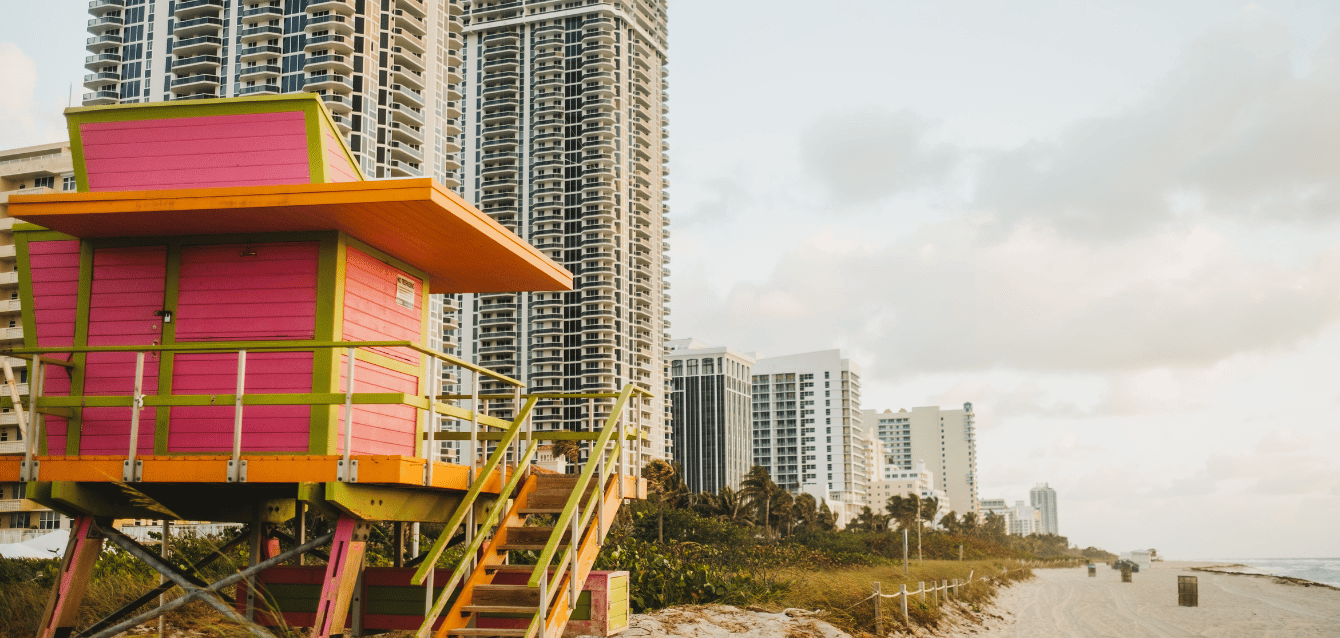 Vibrant lifeguard hut on a Miami beach with high-rise buildings in the background, representing WaveBNB’s success in using social media to drive direct bookings and reduce marketing costs for shor