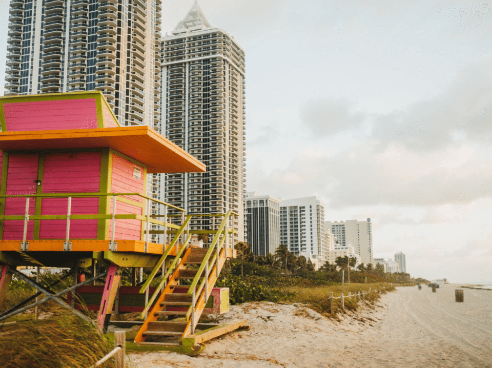 Vibrant lifeguard hut on a Miami beach with high-rise buildings in the background, representing WaveBNB’s success in using social media to drive direct bookings and reduce marketing costs for shor