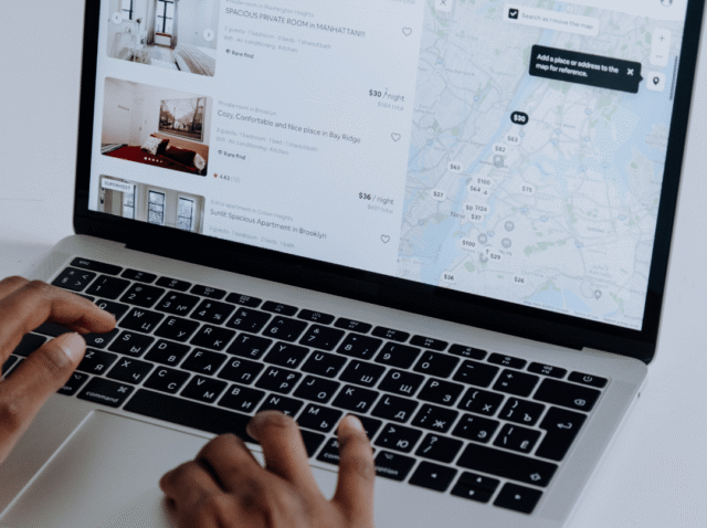 User browsing Airbnb listings with map and prices visible on laptop screen